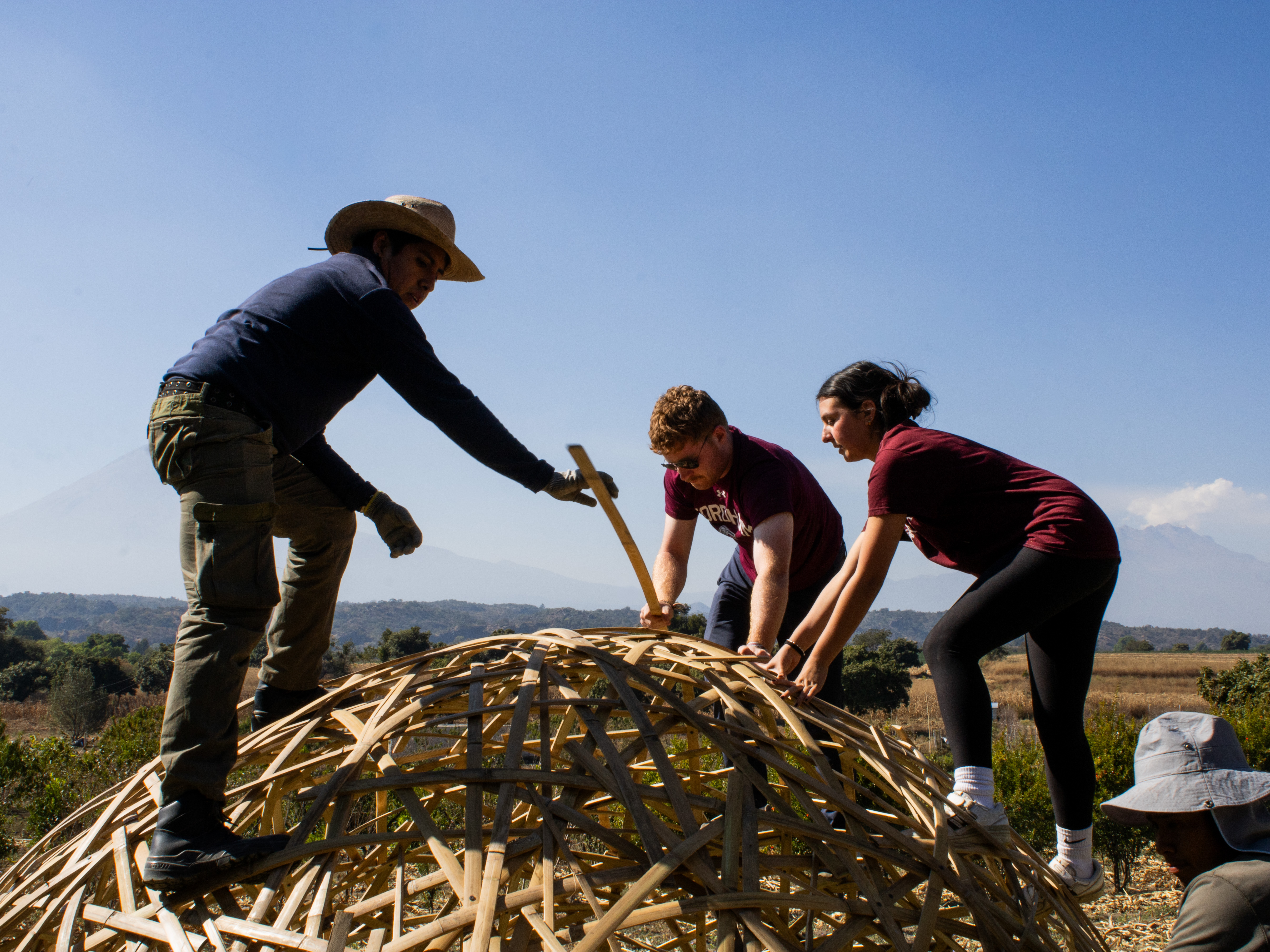 Volunteers and a local builder fastening the bamboo lattice of a dome