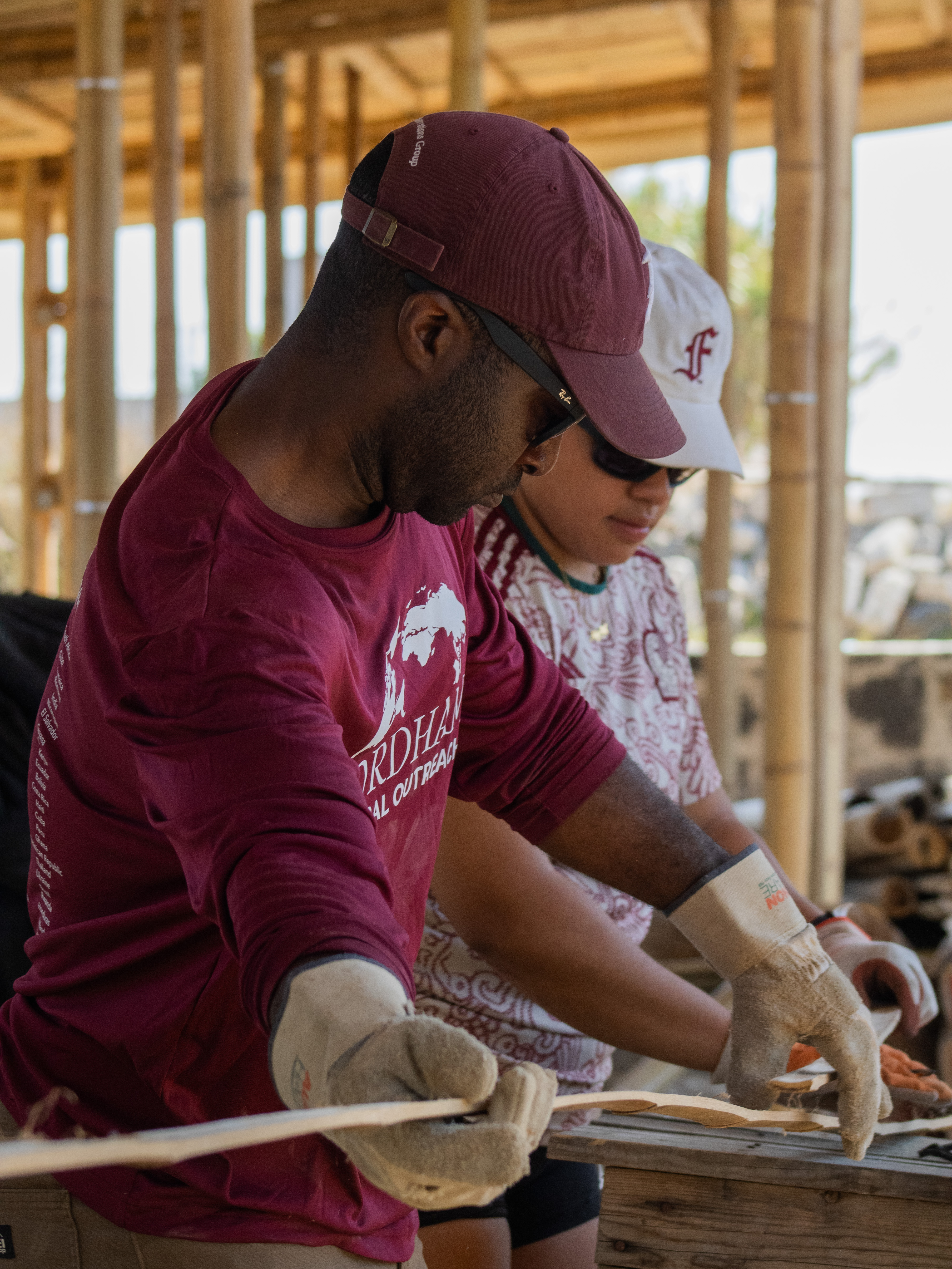Two volunteers working with bamboo at a build table